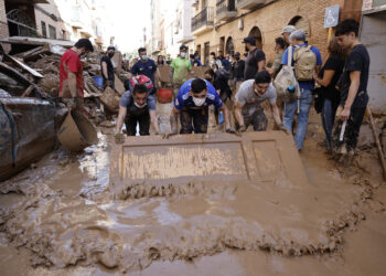 PAIPORTA (VALENCIA), 02/11/2024.- Varias personas retiran el lodo acumulado en una calle de la localidad valenciana de Paiporta, este sábado. Por tercer día consecutivo una marea de voluntarios ha llegado este sábado a barrios del sur de la ciudad de València y a los pueblos de la comarca vecina de lHorta Sud asolados por la dana para luchar contra un fango, donde grupos especializados de los equipos de intervención buscan cadáveres en garajes o fosos aún anegados.EFE/ Biel Alino