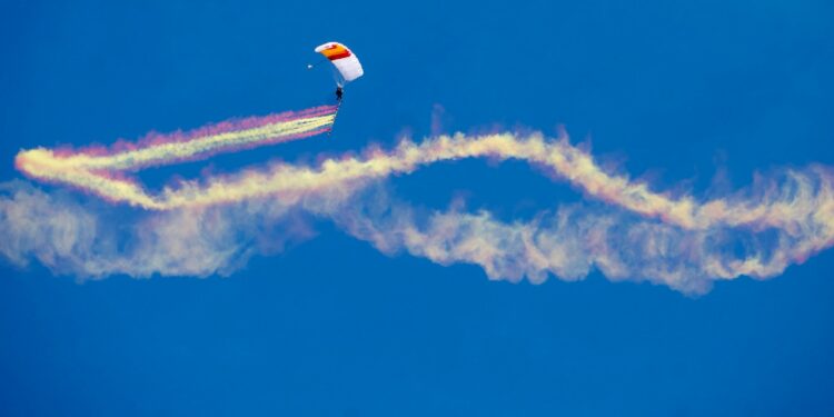 Un paracaidista forma en el salto una bandera de España con humo de colores